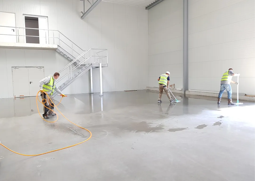 Drei Arbeiter reinigen eine Lagerhalle